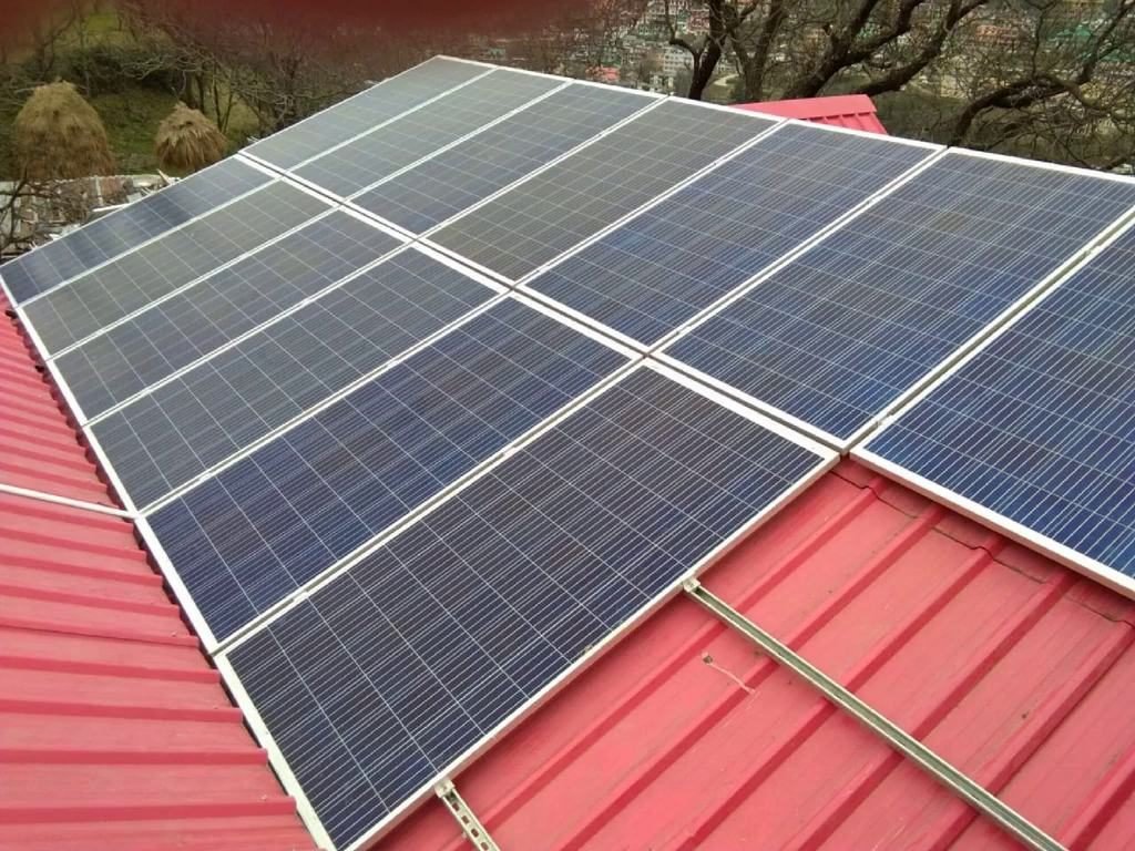 Residential rooftop solar installation on a hillside home in Himachal